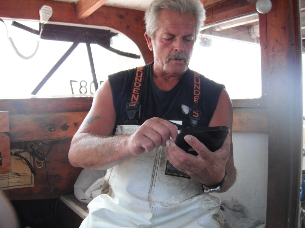 MD Blue Crab Design Team member and active EM pilot project participant, David Kirwin, uses a tablet to submit daily harvest reports from his boat Photo Credit: Ward Slacum