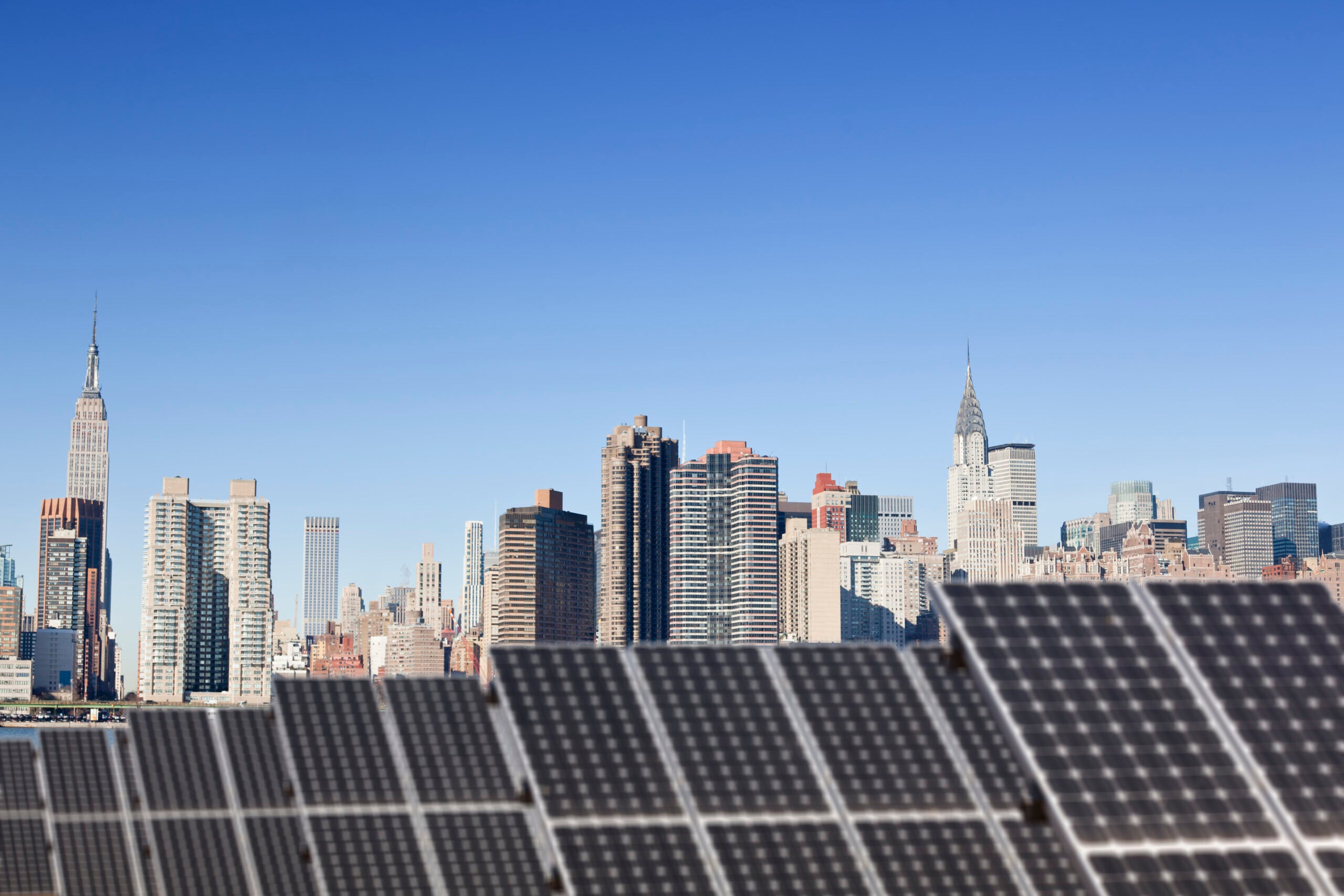 A small solar array in the foreground with the Manhattan skyline in the background.