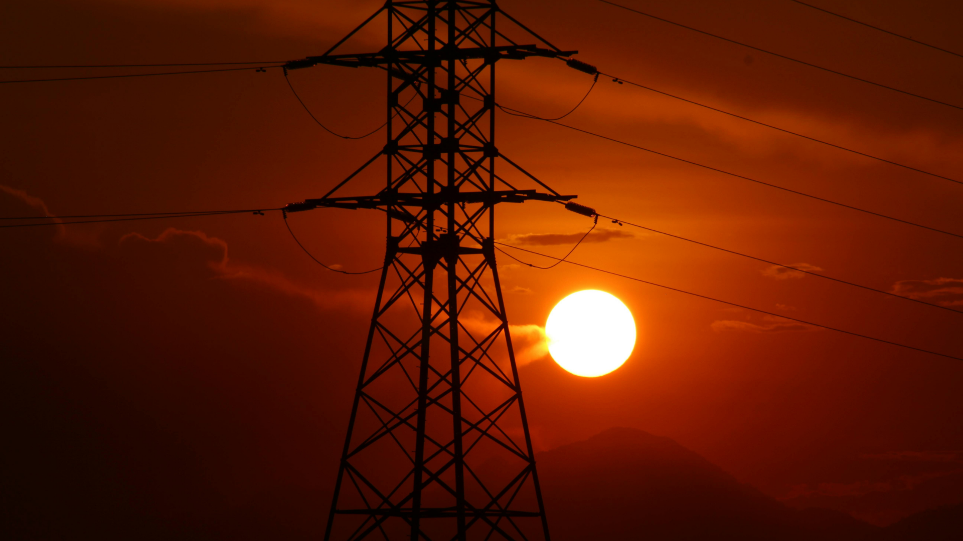 A transmission line silhouetted against a sunset