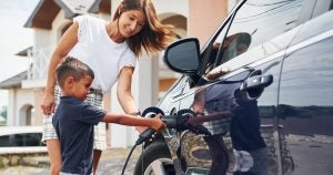 Mom helping young son charge electric car