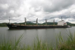 Hong Kong-based and Chinese-flagged cargo ship Heng Chang going through the canal past the town of Gamboa showing the jungle comes right down to the banks of the canal.