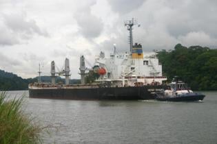 Hong Kong-based and Chinese-flagged cargo ship Heng Chang going through the canal past the town of Gamboa showing the jungle comes right down to the banks of the canal.