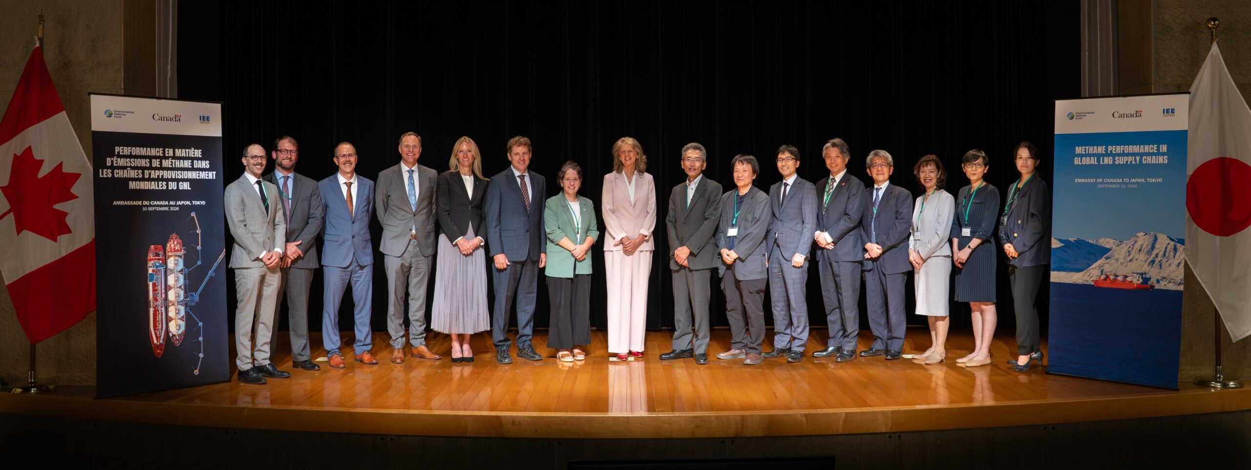 Group of panelists standing in a line between the Canadian and Japanese flags