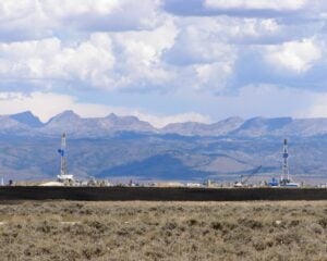 Two oil derricks with a mountain background