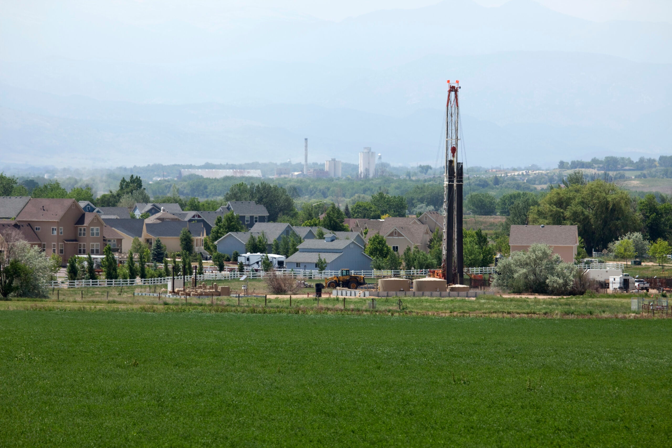 Just off Interstate Highway 25, Drill Rig 1548 - Encana Natural Gas, works closely in front of homes in the town of Frederick in Weld County, Colorado. Haze and pollution block a clear view of the Rocky Mountains in the background.