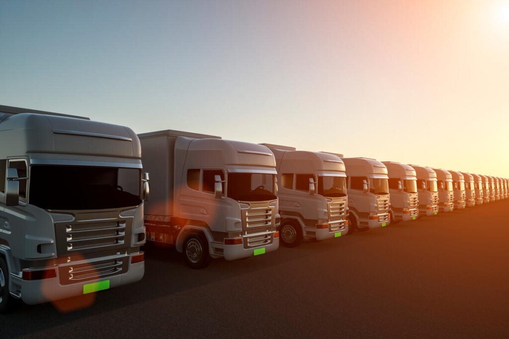Row of cargo electric trucks against with sun