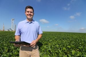 Farmer Scott Henry stands in a soybean field with a tablet computer.