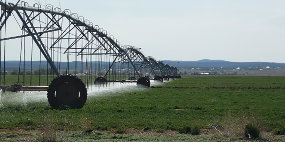 Center pivot on green field with mountains in background.