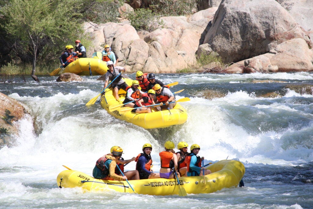 Three rafts with students on river rapids
