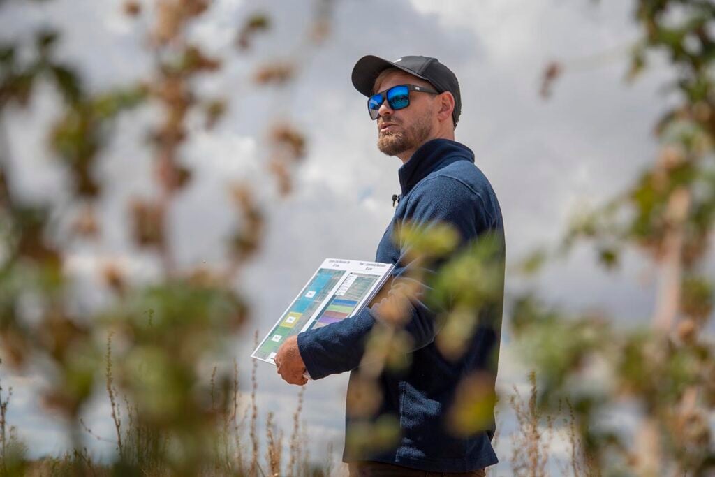 Daniel Toews holding up map with shrubs in foreground
