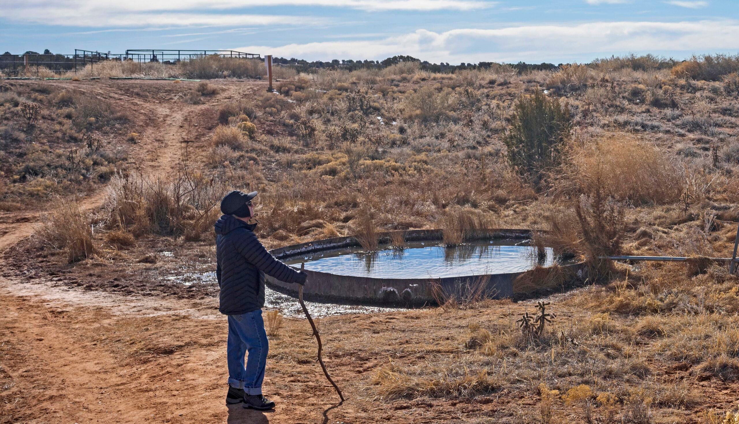 Man by water collection pond surrounded by open land